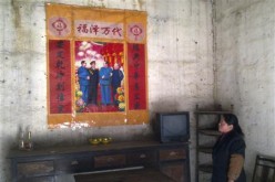 A Chinese villager looks up at a political poster.