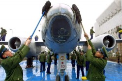 PLAAF soldiers clean up a bomber plane on display at a military museum.