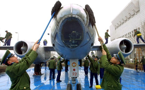 PLAAF soldiers clean up a bomber plane on display at a military museum.