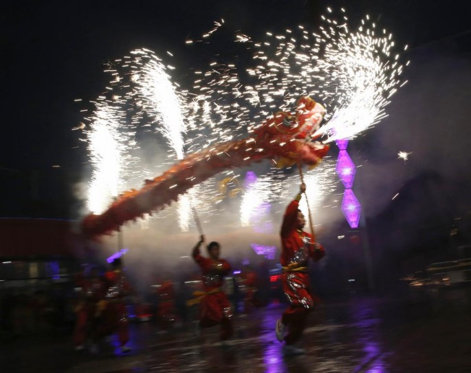 A dragon mascot sets off firecrackers during the advent of the Year of the Sheep.
