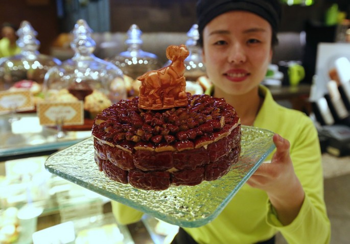 A waitress poses with a cake decorated with a goat-shaped chocolate, which is painted with edible gold powder, to celebrate the upcoming Chinese Lunar New Year.