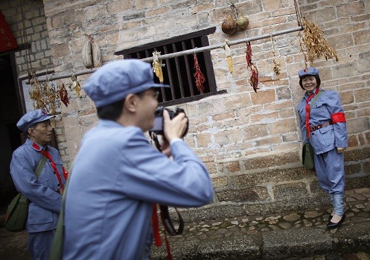 A tourist had a picture taken at an old house where Chairman Mao formerly lived.