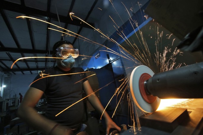 A worker operates a lathe machine as he makes a steel cutter at a manufacturing unit in Noida, on the outskirts of New Delhi, Nov. 3, 2014. 