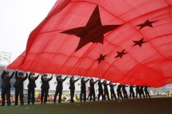 People's Liberation Army (PLA) soldiers wave a Chinese national flag for National Day in Beijing.
