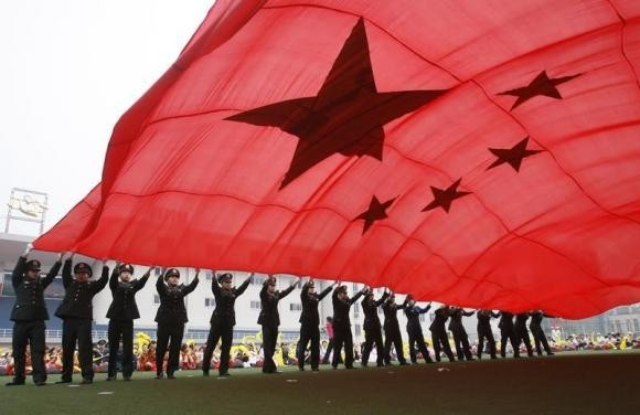 People's Liberation Army (PLA) soldiers wave a Chinese national flag for National Day in Beijing.
