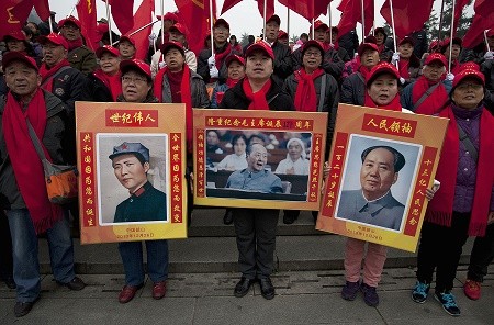 People hold posters of former Communist Party leader Mao Zedong during his 121st birth anniversary.