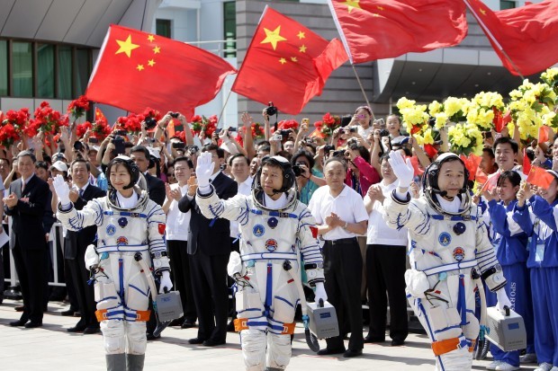 Three Chinese astronauts wave to the crowd before boarding the Shenzhou-9 that will bring them to an orbiting space module.