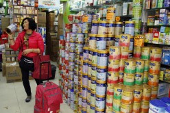 A shopper asks for the price of a canned infant formula at a store in Hong Kong in Feb. 2015. 