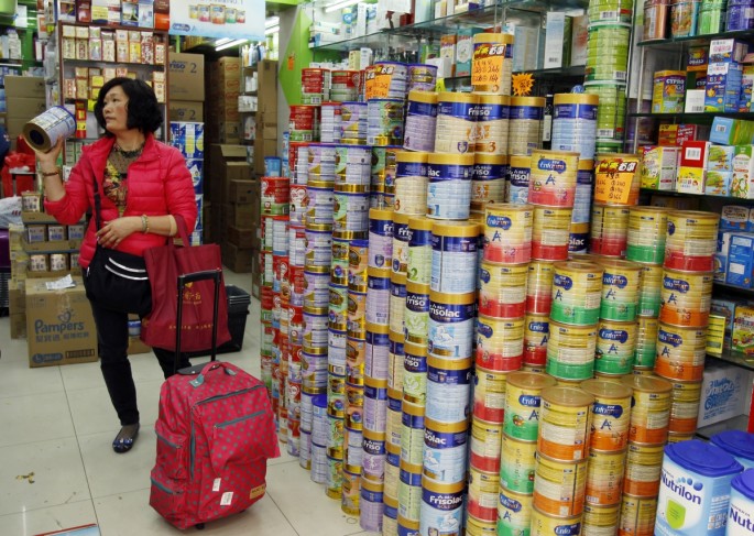 A shopper asks for the price of a canned infant formula at a store in Hong Kong in Feb. 2015. 