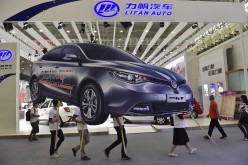 Employees carry an ad for an SAIC Motor car during the Wuhan 2014 Motor Show. 