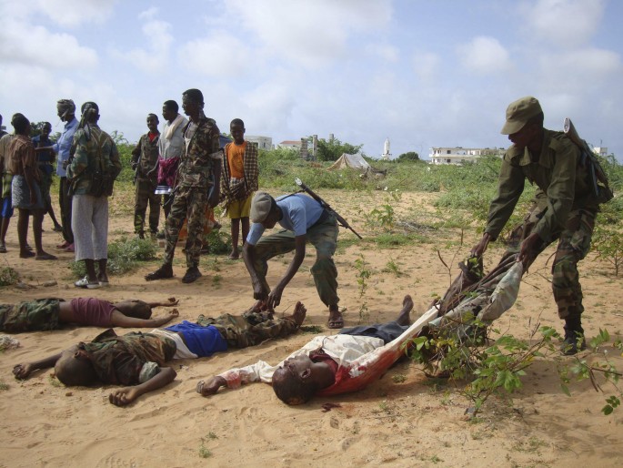 A Somali government soldier drags the dead body of an Islamic al-Shabab fighter killed during fighting