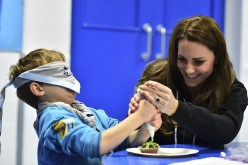 Britain's Catherine, Duchess of Cambridge, helps a blindfolded boy, Fynley Gooch, 7, ice a cake as she promotes disability awareness while meeting with children at the newly established 23rd Poplar Beaver Scout Colony in east London December 16, 2014. 