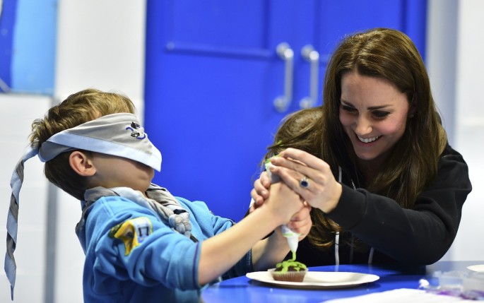 Britain's Catherine, Duchess of Cambridge, helps a blindfolded boy, Fynley Gooch, 7, ice a cake as she promotes disability awareness while meeting with children at the newly established 23rd Poplar Beaver Scout Colony in east London December 16, 2014. 