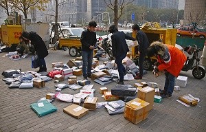 Packages ordered online to be delivered by express companies are sorted on a walkway outside an office building in central Beijing.