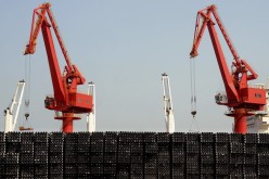 Piles of steel pipes to be exported are seen in front of cranes at a port in Lianyungang, Jiangsu Province, March 7, 2015. 