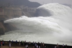 Visitors watch water gushing from the section of the Xiaolangdi Reservoir on the Yellow River during a sand-washing operation in Jiyuan, Henan Province, June 22, 2013. 
