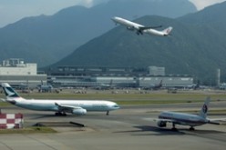 A passenger plane flies over a Cathay Pacific Airways passenger plane at the Hong Kong Airport.