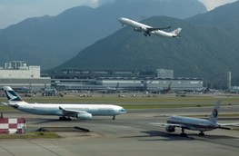 A passenger plane flies over a Cathay Pacific Airways passenger plane at the Hong Kong Airport.