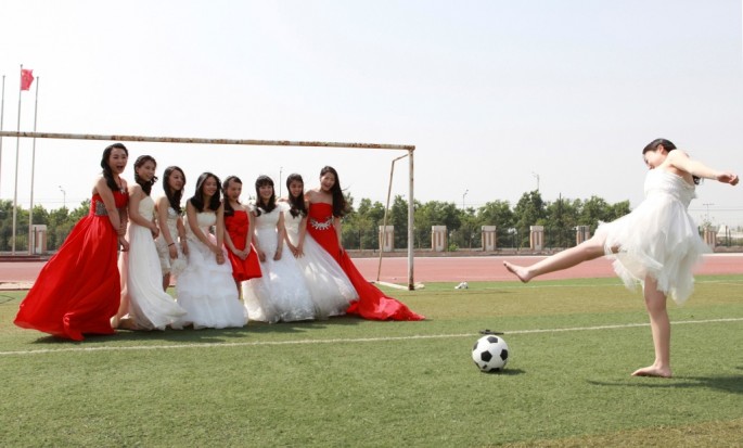 College graduates pose for a photograph with a soccer ball and a goal post on a soccer field at Yuncheng University in Yuncheng, Shanxi Province.