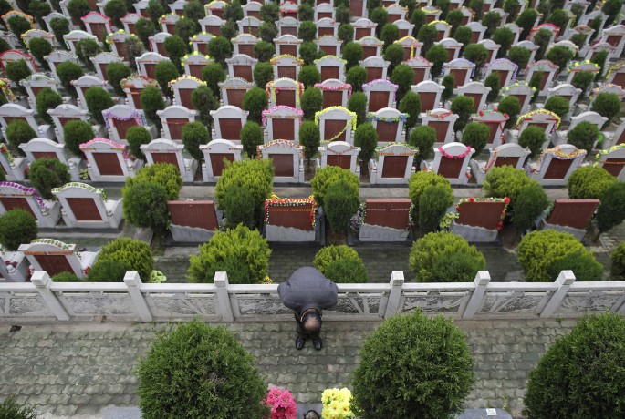 A man bows to the tomb of a relative during the Qingming Festival, or Tomb Sweeping Day, at a public cemetery in Wuhan, Hubei Province, April 5, 2014. 