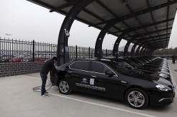 A man charges the batteries of BAIC Motors electric cars at a charging station at the Beijing Capital International Airport in Beijing.
