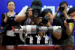 Photographers take pictures of a model of the Shenzhou-9 manned spacecraft (R) docking with the orbiting Tiangong-1 space lab module (L) at the Jiuquan Satellite Launch Center in northwest China. 