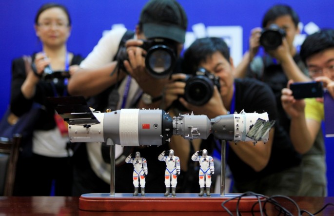 Photographers take pictures of a model of the Shenzhou-9 manned spacecraft (R) docking with the orbiting Tiangong-1 space lab module (L) at the Jiuquan Satellite Launch Center in northwest China. 