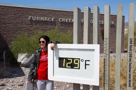 A student from China poses in front of an unofficial temperature gauge at the Furnace Creek Visitor Center in Death Valley National Park in California.
