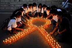 Staff members of a government-run pharmaceutical college light candles