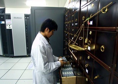 A Chinese scientist looks at stored data tapes located adjacent to a supercomputer at the Beijing Genomics Institute in Beijing.