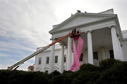 Workers hoist a pink ribbon in honor of breast cancer awareness on the front of the White House in Washington, October 26, 2009. 