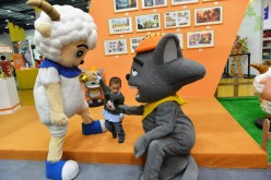 A boy interacts with two cartoon figures during 2015 China International Cartoon and Animation Festival in Hangzhou, Zhejiang Province, on Tuesday, April 28, 2015. 