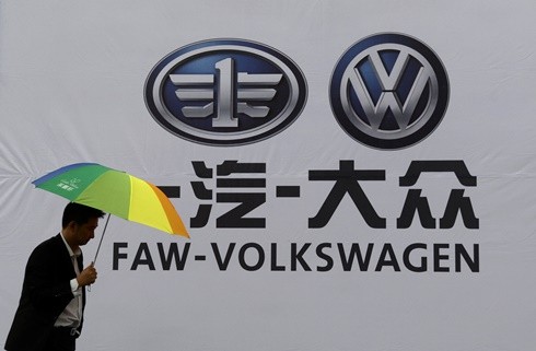 A man walks past a company logo of FAW-Volkswagen at an automobile exhibition in Fuyang, Anhui Province.