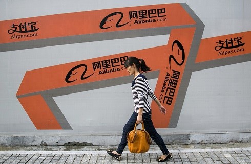 A woman walks past an Alibaba advertisement on a wall in Hangzhou, Zhejiang Province.