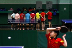A coach talks to students as another hits a shot during a table tennis class at the Shichahai Sports School in Beijing.