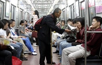 An elderly beggar tries to solicit money from subway passengers on a Beijing subway train. 