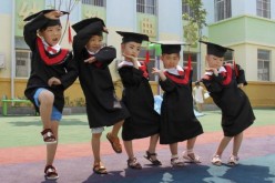Children strike unique poses in their kindergarten graduation gown.
