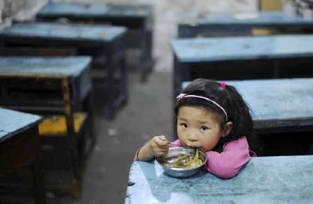 A lone child eats inside a classroom.