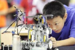 A young inventor tinkers with a robot at a competition and robot exhibition in Tianjin.