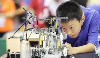 A young inventor tinkers with a robot at a competition and robot exhibition in Tianjin.