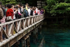 Crowds of tourists take photos on a bridge overlooking the Wuhua Hai Lake at Jiuzhai Valley National Park in China's Sichuan Province.