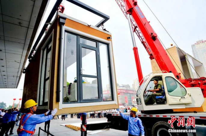 Construction workers erect a modular building at Shijianzhuang, Hebei Province, on June 20, 2015.