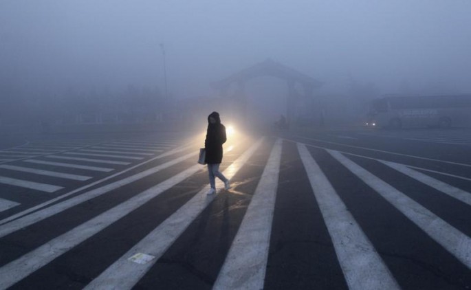A woman walks along a street during a smoggy day in Changchun, Jilin Province, Oct. 22, 2013.