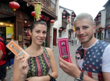 Foreign tourists show some items they bought in Suzhou, East China's Jiangsu Province.