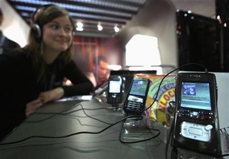 A young woman happily listens to music on a cell phone.