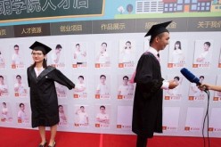 Two of Kunming University's new graduates pose for pictures with the profiles of excellent graduates for the Kunming University Talent Store on Taobao.