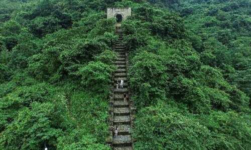 An aerial shot of the Hailongtun in Guizhou Province shows tourists ascending its ancient stairs.