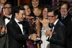 Jimmy Fallon hands off the Emmy to Stephen Colbert as Colbert accepts the award for Outstanding Variety Series for Comedy Central's 
