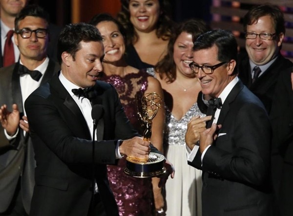 Jimmy Fallon hands off the Emmy to Stephen Colbert as Colbert accepts the award for Outstanding Variety Series for Comedy Central's "The Colbert Report" at the 66th Primetime Emmy Awards.