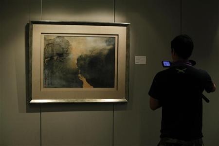 A cameraman films "Morning Mist in Spring," an artwork by artist Zhang Daqian, at an auction in Hong Kong in this Sept. 1, 2011 photo.